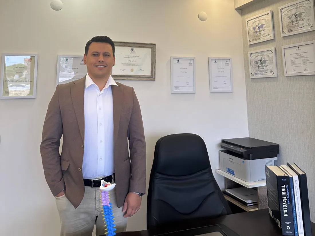 Fizyoterapist Anıl Güler, Bandırma'daki kliniğinin çalışma odasında; arkasındaki duvarda diploması ve osteopati sertifikaları asılı